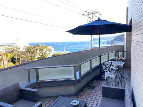 a balcony with a table and an umbrella at Atami Onsen Guest House Megumi 5 minutes walk from Atami Station in Atami