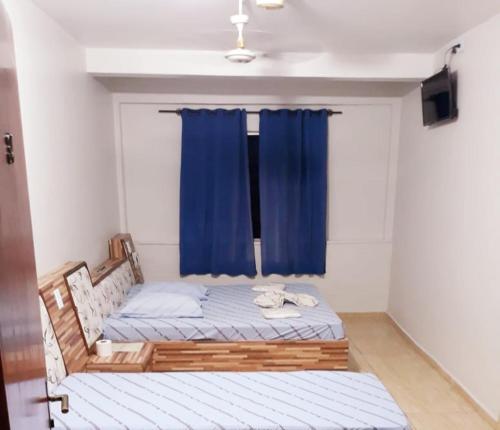 a bedroom with a bed with a blue curtain at Hotel Mustang in Sao Paulo