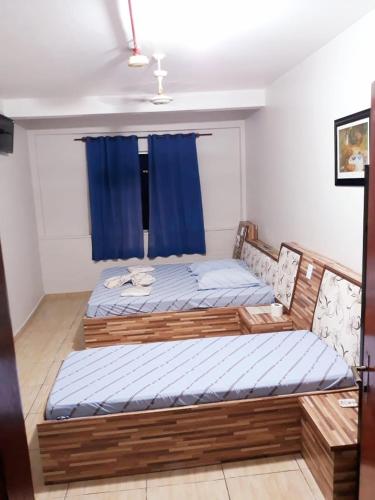 two twin beds in a room with blue curtains at Hotel Mustang in Sao Paulo