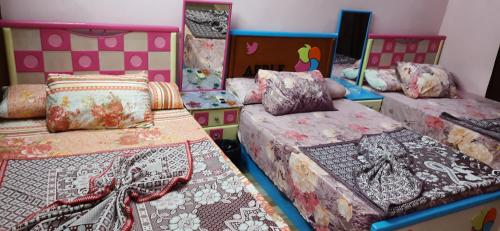 a room with three beds with blankets and pillows at Al Mansoura Apartment in Mansoura