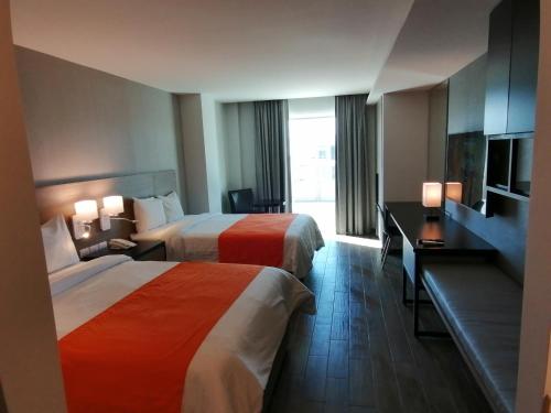 a hotel room with two beds and a television at Hotel Nuvo in Saltillo