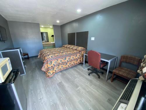 a hotel room with a bed and a desk and a chair at Town House Motel in Tyler