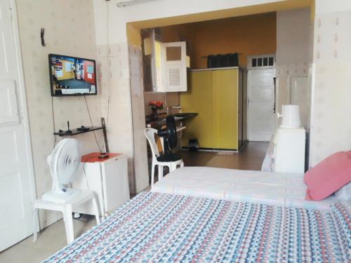 a bedroom with a white bed and a kitchen at Kitnet Mobiliada in São Luís