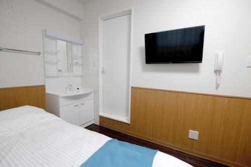 a bedroom with a bed and a tv on the wall at Phoenix Ryukyu Henzanbaru -SEVEN Hotels and Resorts- in Chatan