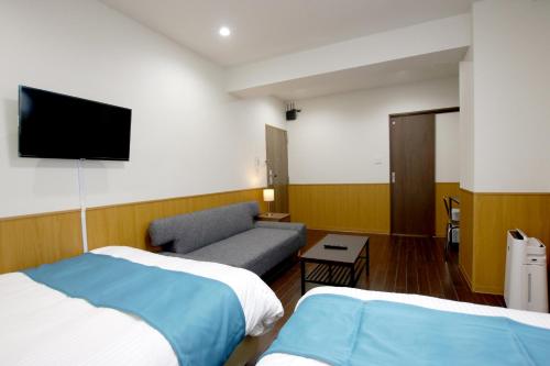 a hotel room with two beds and a couch at Phoenix Ryukyu Henzanbaru -SEVEN Hotels and Resorts- in Chatan