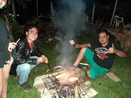 two men are sitting around a grill at Cabañas Guacari San Agustín huila in San Agustín