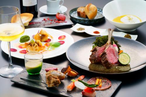 a table with plates of food and a glass of wine at SEKIYA RESORT Galleria Midobaru in Beppu