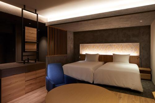 a bedroom with two beds and a blue chair at SEKIYA RESORT Galleria Midobaru in Beppu