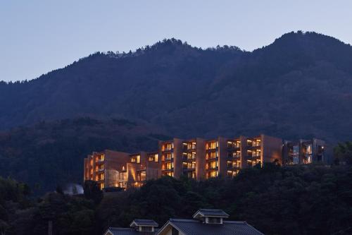 a building on a hill in front of a mountain at SEKIYA RESORT Galleria Midobaru in Beppu