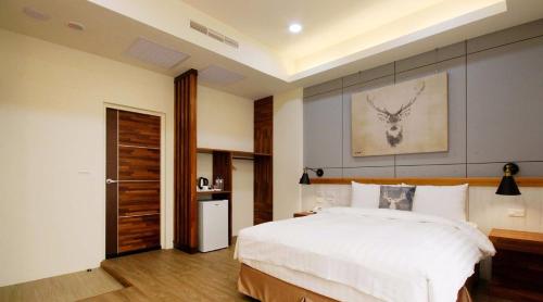 a bedroom with a large white bed with a deer head on the wall at 逐鹿森林民宿-無電梯 in Yuchi