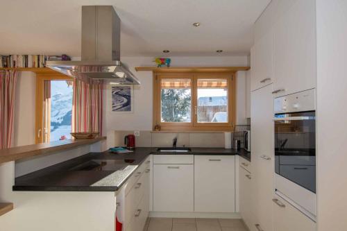 una cocina con armarios blancos y fregadero en Ferienwohnung Gartenweg, en Adelboden