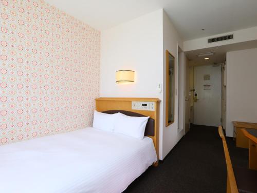 a hotel room with a bed and a desk at Hotel Wing International Tomakomai in Tomakomai