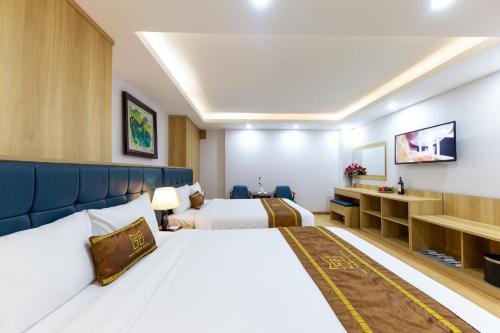 a hotel room with two beds and a tv at Mai Thang Hotel Da Lat in Da Lat