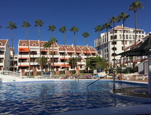een zwembad tegenover een resort met palmbomen bij LUX&2Jacuzzi. NEW! Golden Mile Las Americas, Parque Santiago 2. Pool heated Sea water 2 BDR in Playa de las Americas