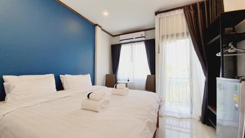 1 dormitorio con 1 cama blanca grande y 2 toallas en Sabua The Terrace Homestay, en Uthai Thani