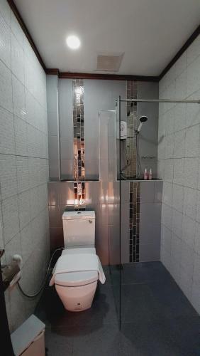 a bathroom with a toilet and a glass shower at Sabua The Terrace Homestay in Uthai Thani