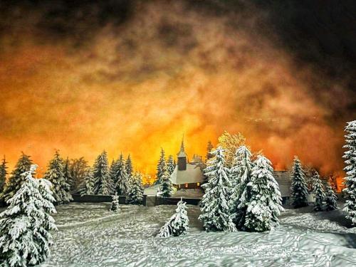 una pintura de un bosque cubierto de nieve con una iglesia en La Monica 2 - Cazare Straja - Lupeni - Retezat - Parang, en Lupeni