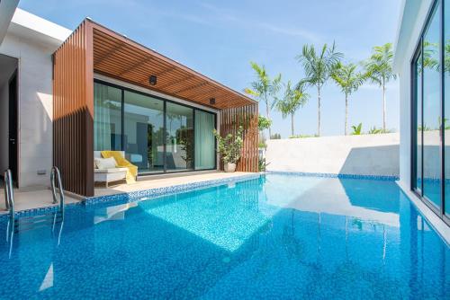 a swimming pool in front of a house at Movenpick Residences 3-Bedroom Pool Villa Beach Access, Na Jomtien Pattaya in Na Jomtien