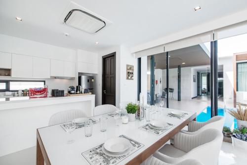 a kitchen and dining room with a table and chairs at Movenpick Residences 3-Bedroom Pool Villa Beach Access, Na Jomtien Pattaya in Na Jomtien