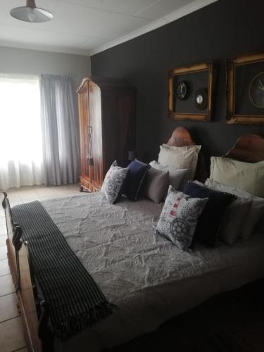 a bedroom with a large bed with many pillows at A-Cody Place in Louis Trichardt