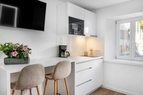 a kitchen with white cabinets and two chairs at Feel like an Emperor Apartments in Split