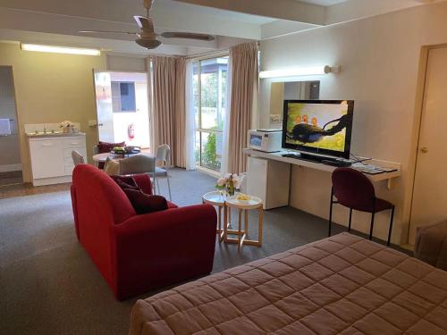 a living room with a red couch and a television at Apollo Motel Parkes in Parkes