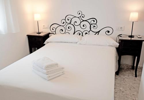Un dormitorio con una cama blanca con toallas. en Hostal Trafalgar, en Barbate