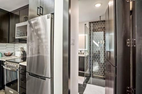 eine Küche mit einem Kühlschrank aus Edelstahl und einer Dusche in der Unterkunft Quantum Tiny Loft at East End Revitalized in Houston