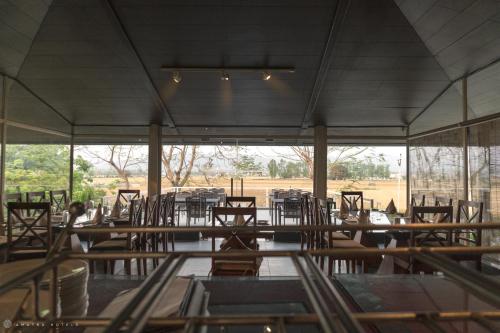 a dining room with tables and chairs and a large window at Amatra By The Ganges in Haridwār