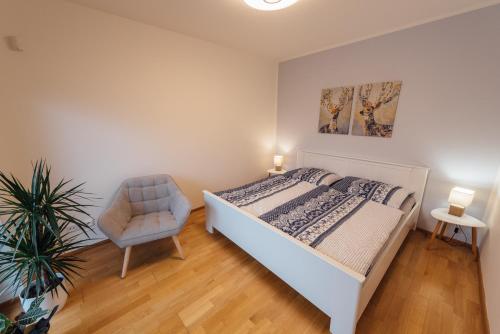 um quarto com uma cama branca e uma cadeira em Apartmán Pod borovicí em Kovalovice
