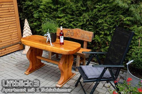 a wooden table with a bottle of wine and a bench at Ferienwohnungen "Liftblick 2 oder 3" im Kurort Altenberg in Kurort Altenberg