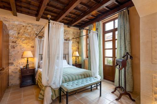 a bedroom with a canopy bed and a window at Palazzino Di Corina in Rethymno