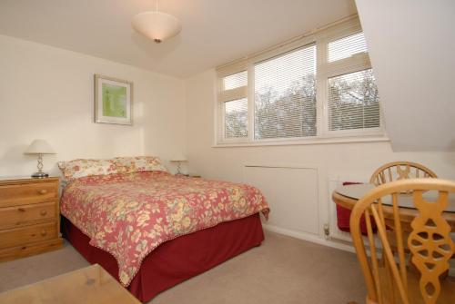 a bedroom with a bed and a dresser and two windows at Abacus Bed and Breakfast, Blackwater, Hampshire in Farnborough