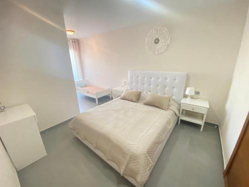 a white bedroom with a bed and a night stand at Cosy apartment - 4 min walk from the beach - La Tejita El Medano in La Tejita