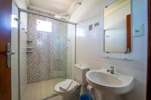 La salle de bains est pourvue de toilettes, d'un lavabo et d'une douche. dans l'établissement Hotel Tadini, à Santa Rita do Sapucaí