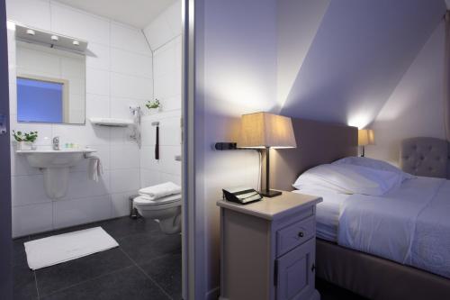 een slaapkamer met een bed en een badkamer met een wastafel bij Hotel La Chaumiere in Asse