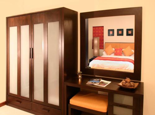 a bedroom with a bed and a mirror on a dresser at The Gardens in Bang Rak Beach
