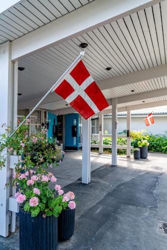 a norwegian flag flying in front of a building with flowers at Strandhotel Balka Søbad in Neksø