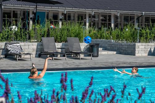 a woman is swimming in a pool with a blue chair at Strandhotel Balka Søbad in Neksø