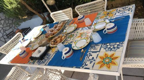 a table with plates and utensils on it at La Draghina B&B Capri in Anacapri