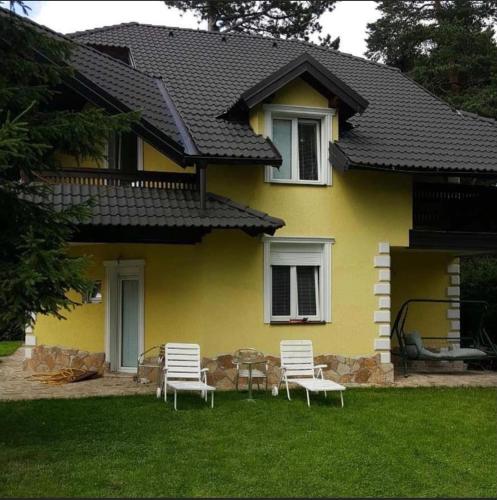 a yellow house with three chairs and a table in the yard at Yellow House in Palisad
