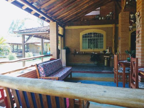 eine Veranda eines Hauses mit einer Bank und einem Tisch in der Unterkunft Sitio Pousada Morada do Sol in Cunha