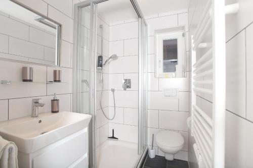 uma casa de banho branca com um lavatório e um chuveiro em Gästehaus Scherrer em Mittelberg
