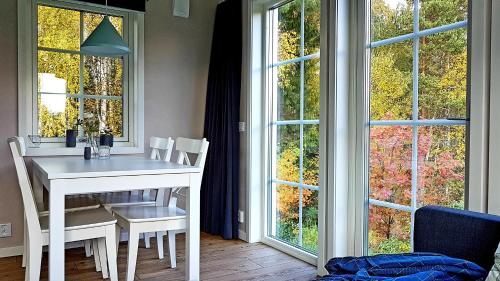 a white table and chairs in a room with windows at Nybyggd stuga intill skogsbrynet - New built cottage next to the cowberry forest in Mora