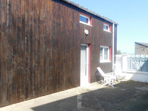 un mur en bois avec une chaise à côté d'un bâtiment dans l'établissement Gîte de la Nouasse, à Québriac