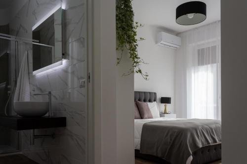 - une chambre blanche avec un lit et un lavabo dans l'établissement B&B La maison foggia, à Foggia