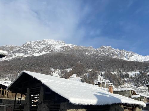 a snow covered roof of a building with a mountain in the background at Chalet dei Reparti Bormio in Bormio