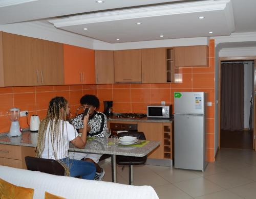 zwei Frauen an einem Tisch in einer Küche in der Unterkunft Delux Appartment in Praia