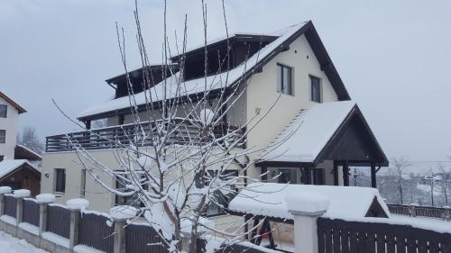 a white house with snow on the roof at Casa Aryana, adults only in Bran