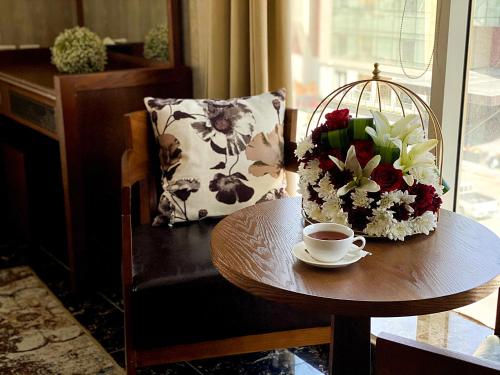 a table with a cup of coffee and a bouquet of flowers at Arto Aparthotel in Riyadh